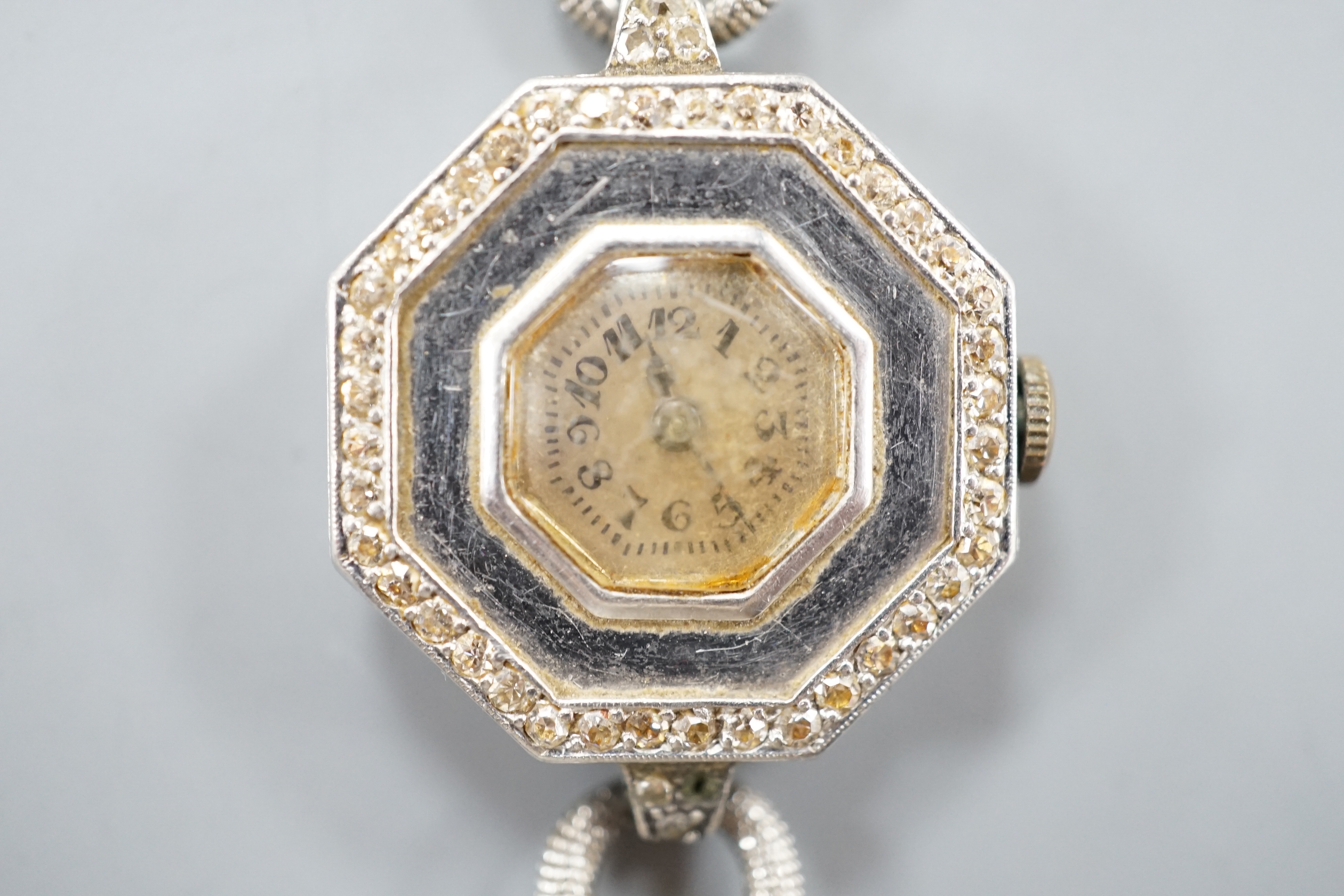 A lady's early 20th century white metal and diamond chip set manual wind octagonal cocktail watch, on a white metal twin strand mesh bracelet, gross 27.4 grams.